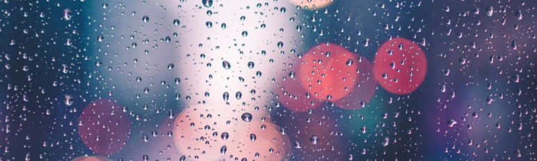 image of raindrops on glass with vehicle lights behind