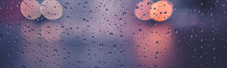 image of raindrops on glass with vehicle lights behind